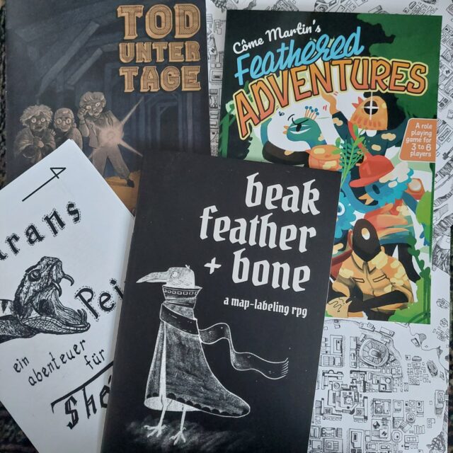 Ein paar Neuzugänge der letzten 4 Monate für meine #Rollenspielbibliothek.
Bisher sind alle noch ungespielt. Aber ich freu mich auf jedes einzelne.

Was davon kennst du, 
besitzt du selbst,
oder hast du schon gespielt?

Beak, Feather + Bone ist ein #Worldbuilding #Erzählspiel, bei dem man eine Stadtkarte mit Leben erfüllt. 

Tod unter Tage ist ein Szenario für #BrindlewoodBay, in dem die Krimikennerinnen eine alte Goldmine erkunden.

Feathered Adventures ist unglaublich schönes, regelarmes Erzählrollenspiel im Stil eines Samstag-Morgen-Cartoons.

Marans Pein ist ein 100% handgemachtes #Zine mit einem #OSR-Modul im klassischen "town with a problem"-Stil.

#pnpde #rollenspiel #ttrpg